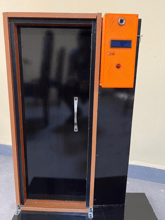 The completed unit mounted on a door frame — an orange enclosure on the jamb beside a full-size black door